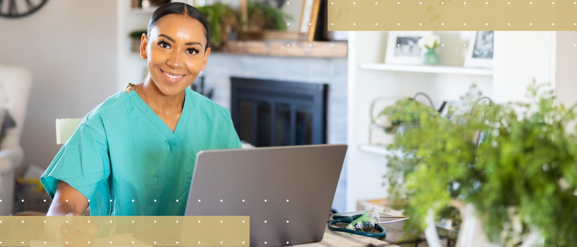 A smiling healthcare professional in teal scrubs works on a laptop at a wooden desk in a bright, plant-filled home office. A stethoscope rests on the desk beside the computer, with a white fireplace and decorative shelving visible in the background.