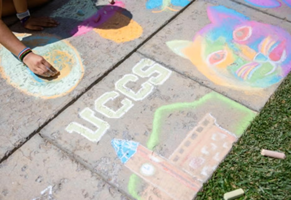 Sidewalk chalk art drawing of "UCCS" with the iconic clocktower.