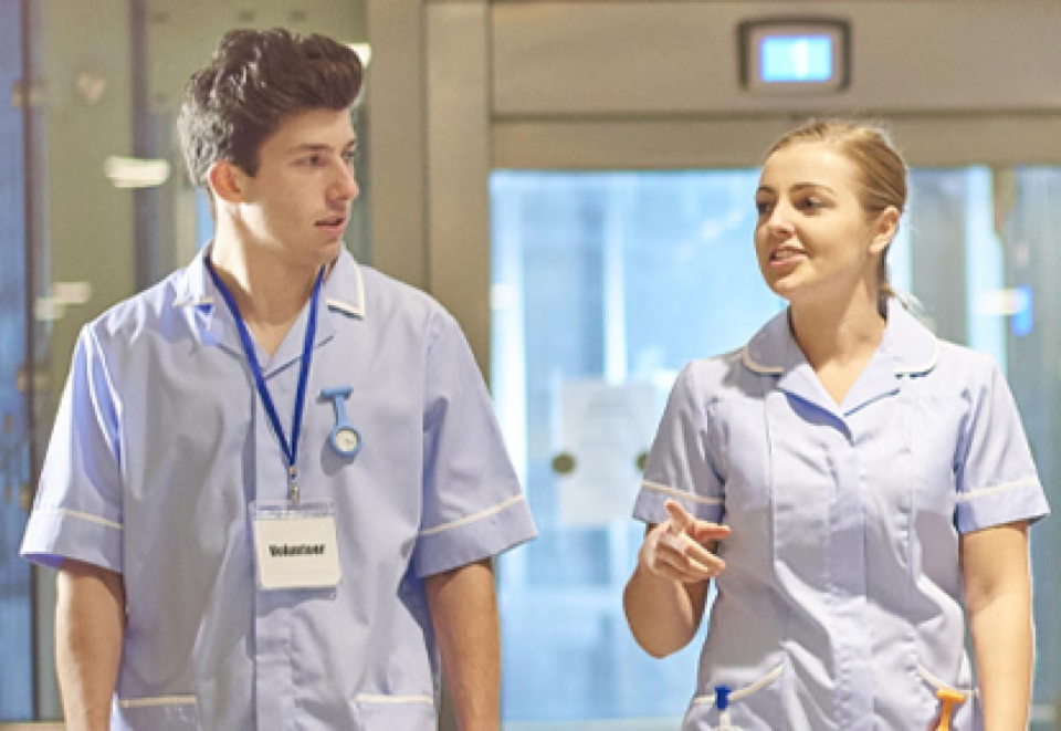 2 healthcare workers walking in a hospital.