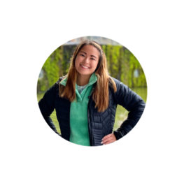 Smiling woman, Ann S. in green hoodie under black coat.