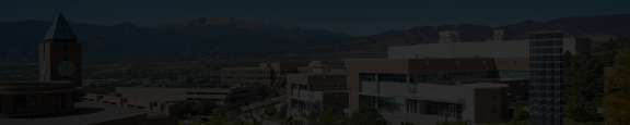 A landscape image of the UCCS campus with the iconic clock tower in the foreground and Pike's Peak mountain in the background, with a dark overlay for text contrast.