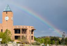 Iconic brick clocktower on the UCCS campus with a rainbow in the background.