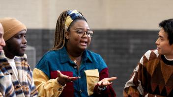 Woman sitting with 3 diverse men and one woman in a discussion circle.