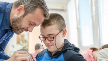 Teacher man with young special education student wearing red glasses.